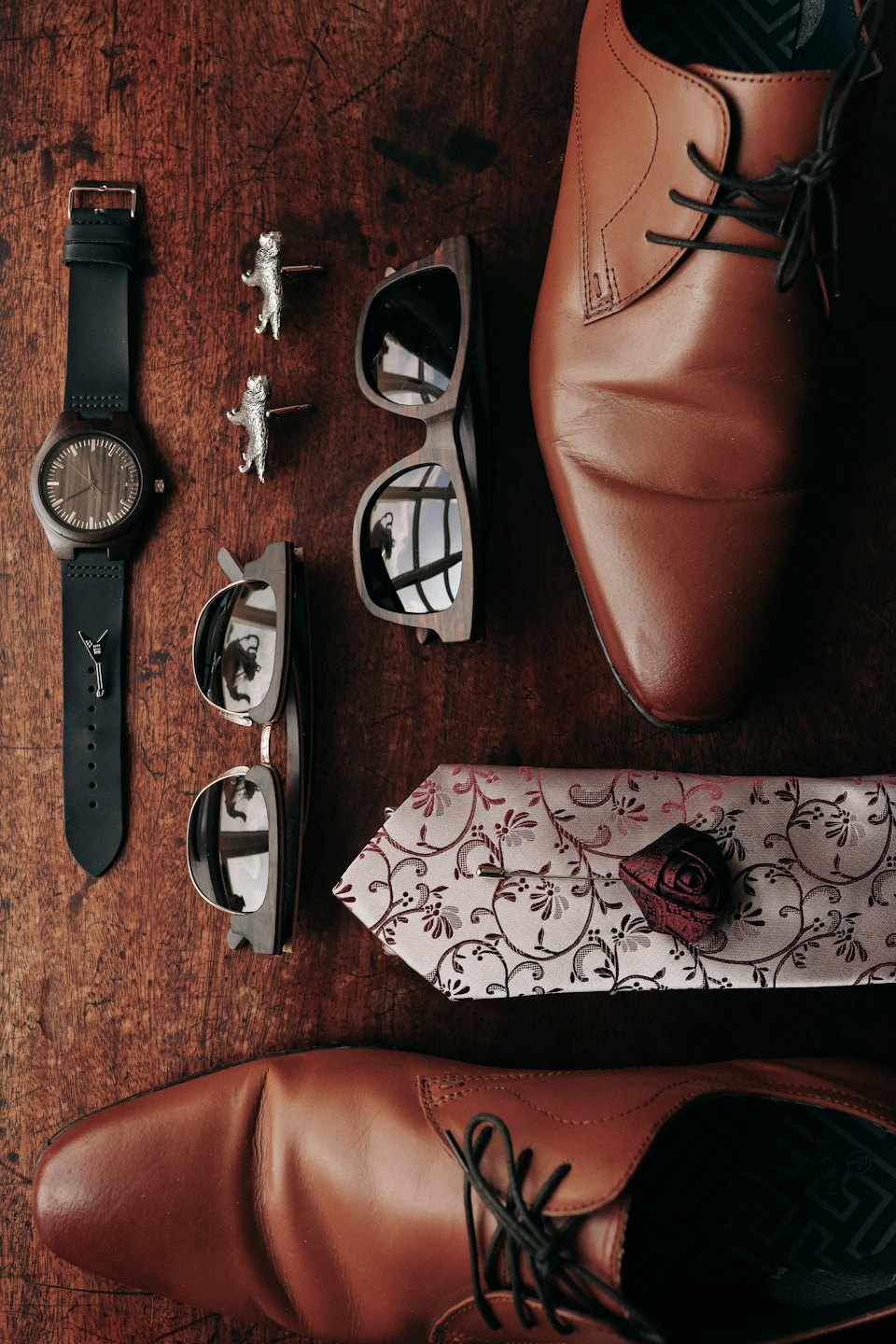 Men's formal accessories laid out on a dark wooden surface.